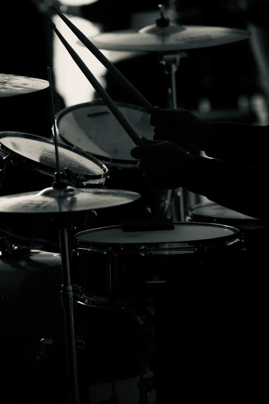 Drumsticks over a drum kit in black and white